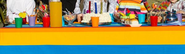 Colorful kids' party table with cake, juice, and treats.