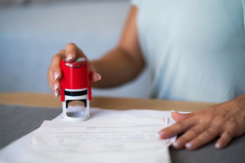 Close-up of unrecognizable businesswoman stamping a document in the office