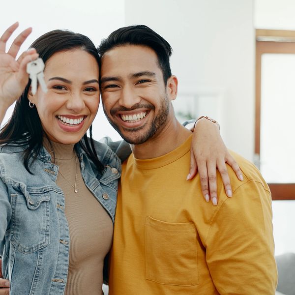 Happy couple holding keys, celebrating new home.