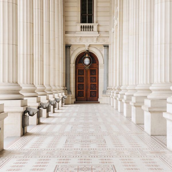 Symmetrical corridor with classical columns and ornate wooden door.