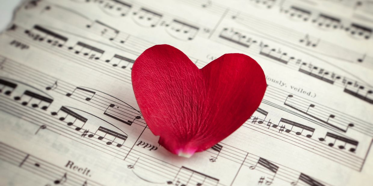Red heart-shaped petal on music sheet.