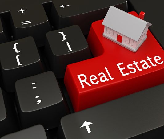 Red keyboard key labeled 'Real Estate' with a small house model on it.