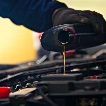Pouring motor oil into a car engine.