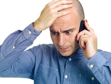 Worried man talking on cellphone.