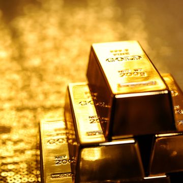 Stack of shiny gold bars reflecting warm light.