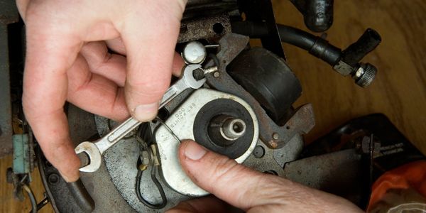 Hands repairing a mechanical part with a wrench.