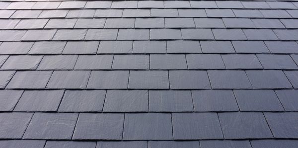 Close-up of dark grey roof tiles with a neat ridge cap.
