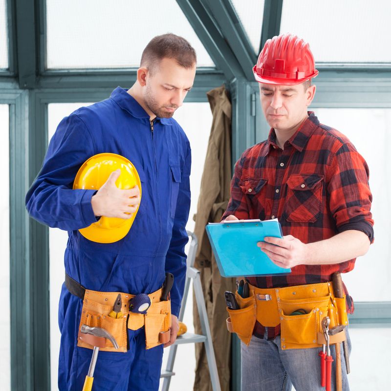 Construction workers consulting and looking at the plans on a building site.