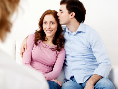 A couple embraces while sitting on a couch, sharing a tender moment.