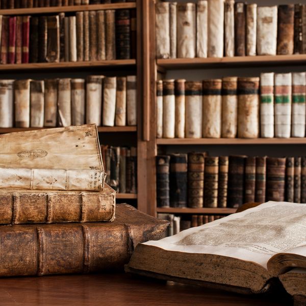 A collection of old, leather-bound books in a vintage library setting.