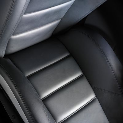 Close-up of a sleek black leather car seat with detailed stitching.