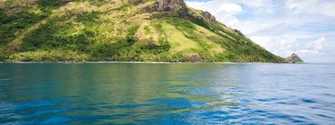 Scenic view of a mountain by the ocean under a blue sky.