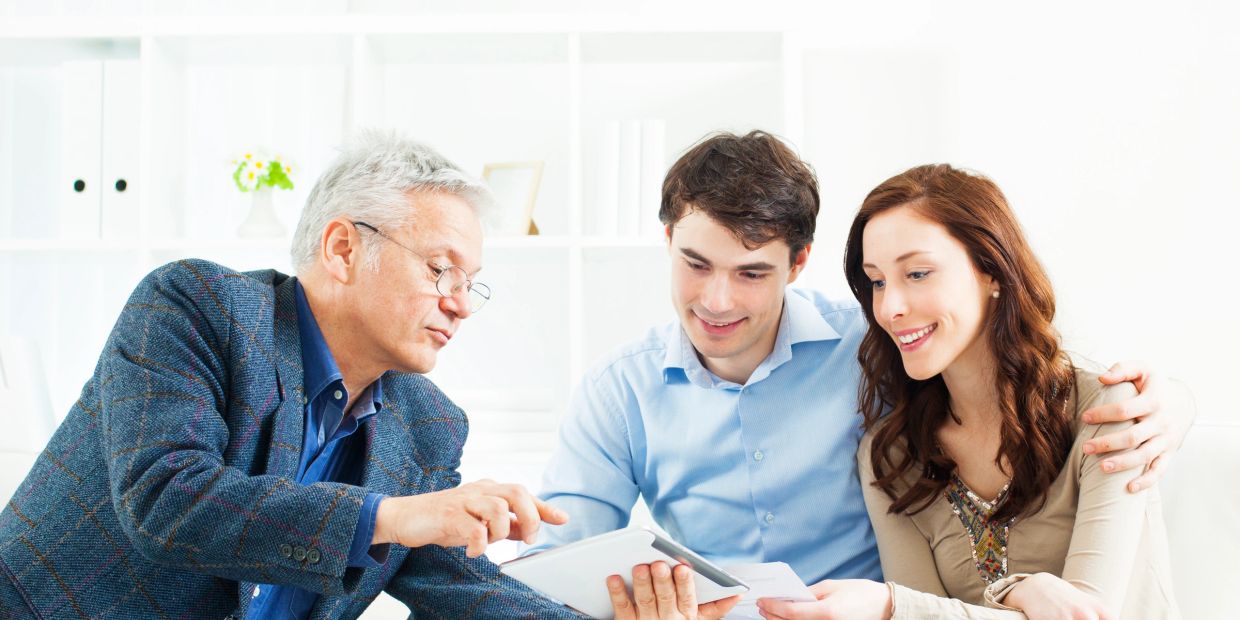 Financial advisor explaining documents to a couple in a bright office.