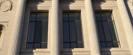 Tall classical columns in front of large windows on a stone building.