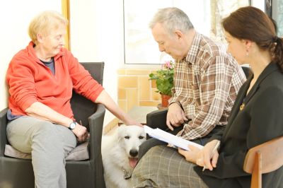 a canine professional sat with 2 owners and their dog and observing the dogs behaviour