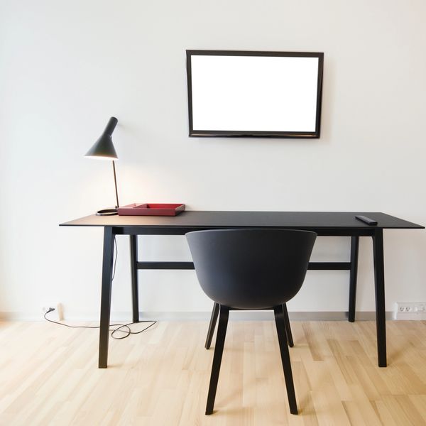 Bureau noir minimaliste avec lampe et chaise.