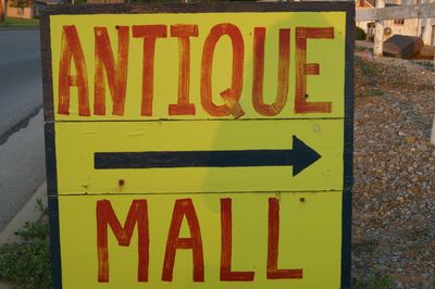 Yellow sign with red letters pointing to an antique mall.