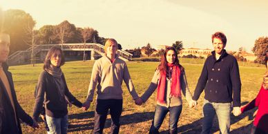 Group of friends holding hands in a sunny park.