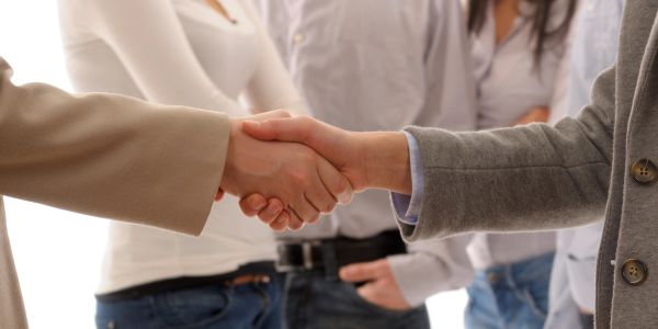 Two people shaking hands in a professional setting.