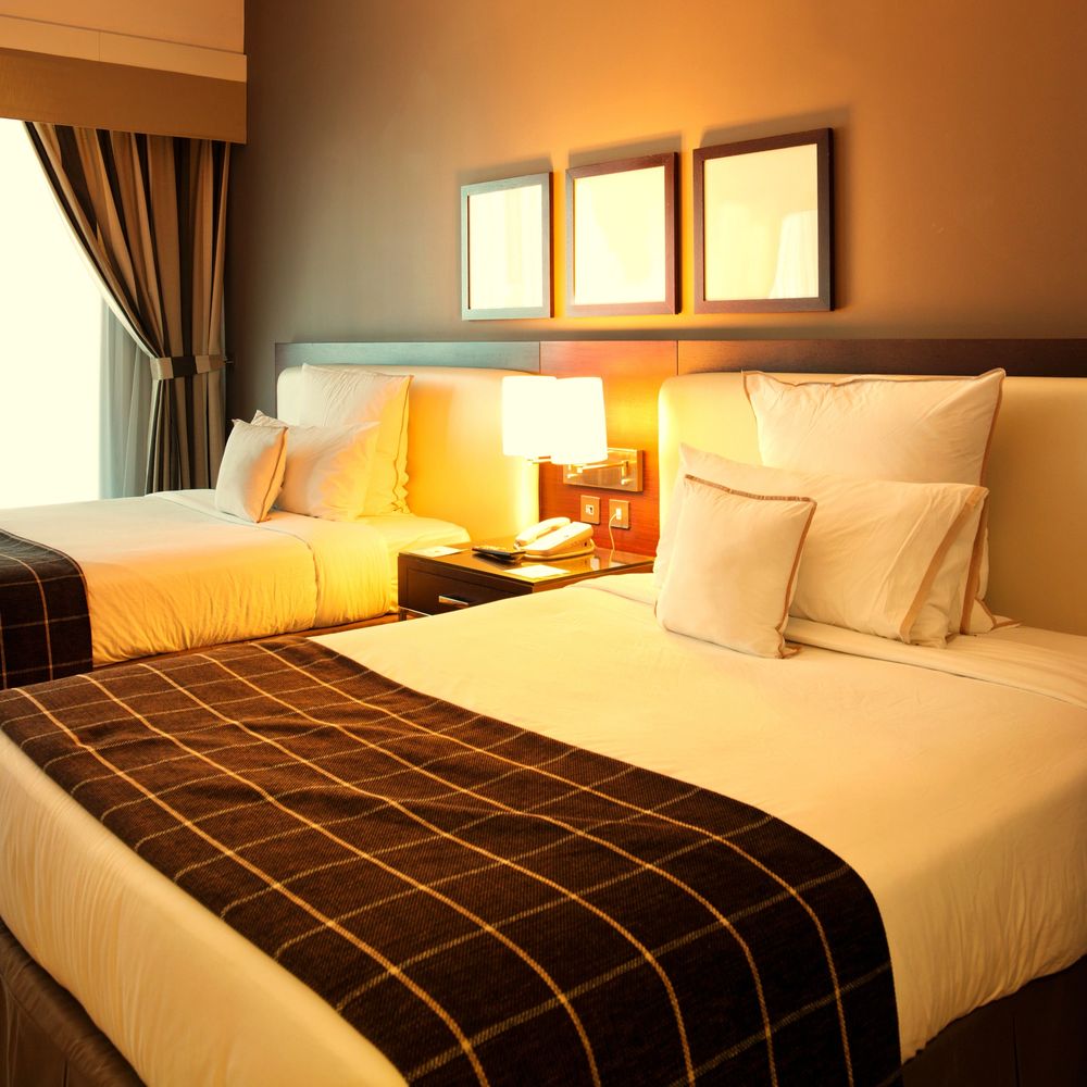 Cozy hotel room with two beds and warm lighting.