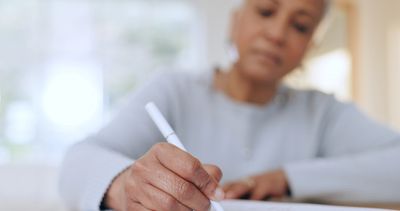 Woman seriously writing in notebook with white pen 