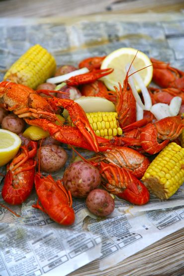 A vibrant seafood boil with crawfish, corn, potatoes, and lemon wedges.