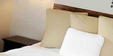 Cozy bed with fluffy pillows and a wooden headboard.