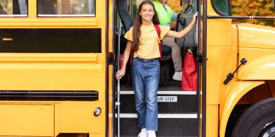 Girl smiling as she gets off a school bus.