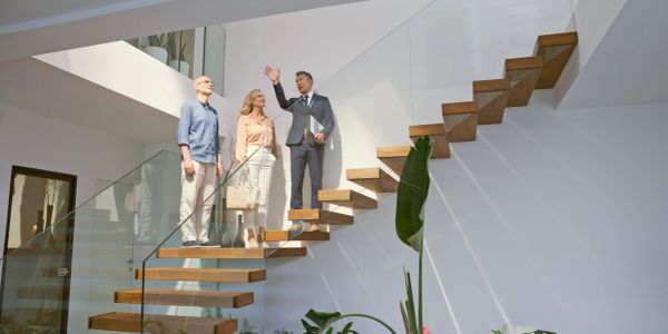 Real estate agent showing a modern home to a couple on floating stairs.