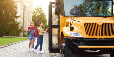 Two girls boarding a yellow school bus.