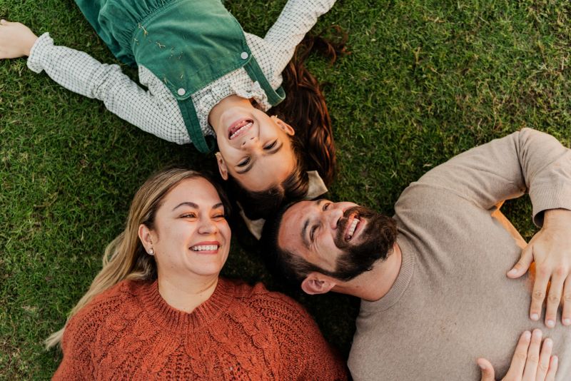 Parents and daughter lying down on ground in public park