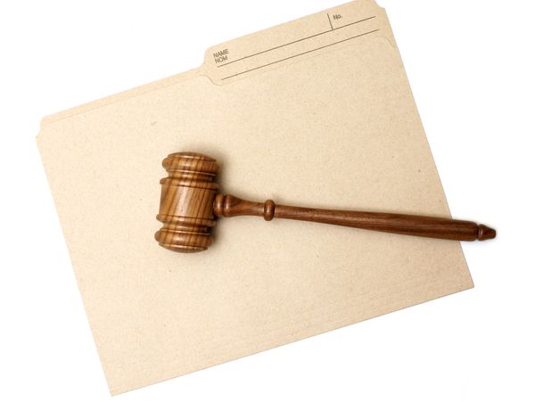 Wooden judge's gavel resting on a beige file folder.