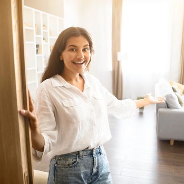 Smiling woman welcoming you into a bright, cozy living room.