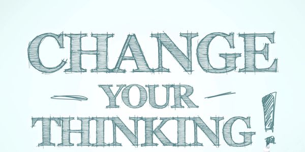 Hand writing the phrase 'Change Your Thinking!' with a marker.