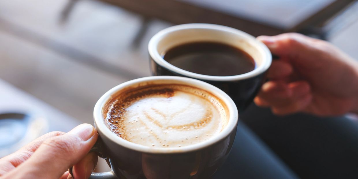 Two cups of coffee being held next to each other by customers