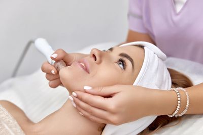 Woman receiving a facial treatment with a handheld device at a spa.