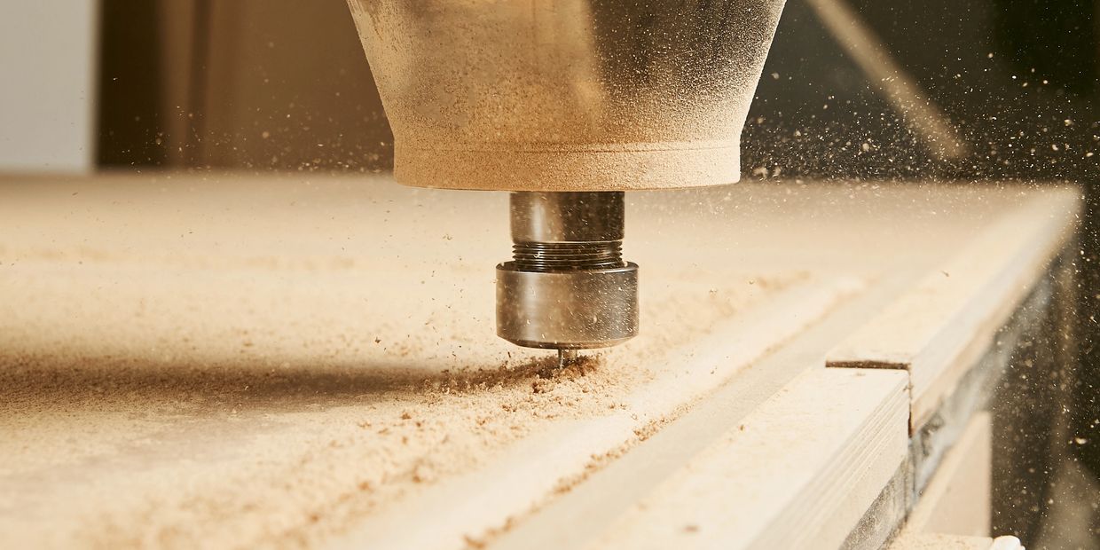 CNC machine carving wood with precision, creating fine sawdust particles.