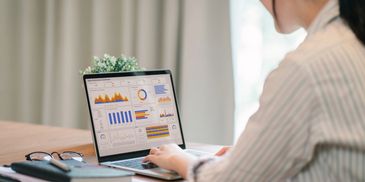 Behind the scenes image of woman looking at marketing analytics on a laptop.
