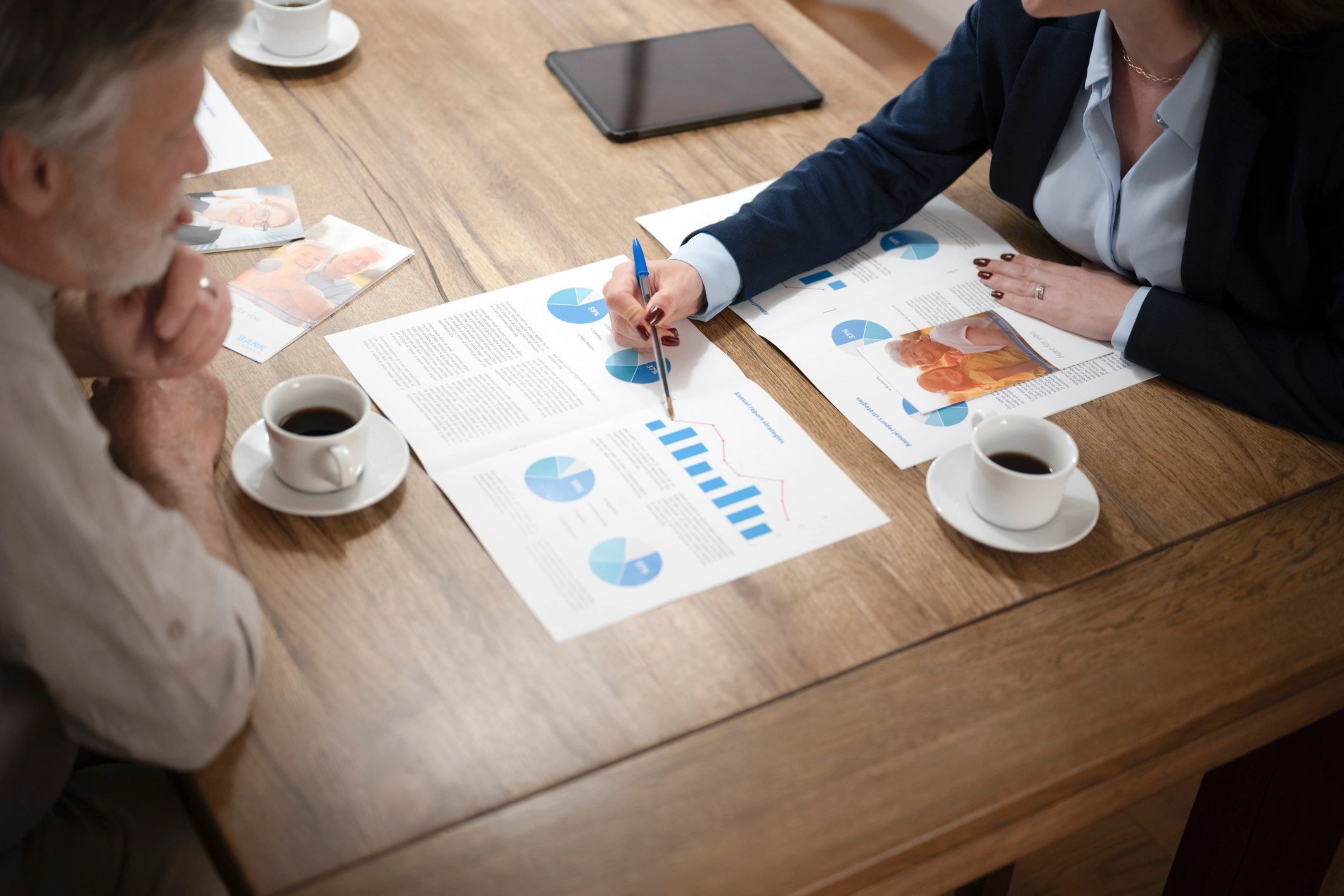 Two people discussing financial documents over coffee.