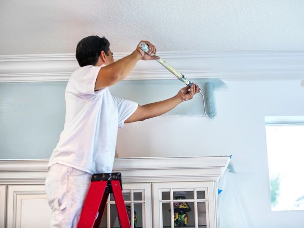 Man rolling wall sideways with light blue