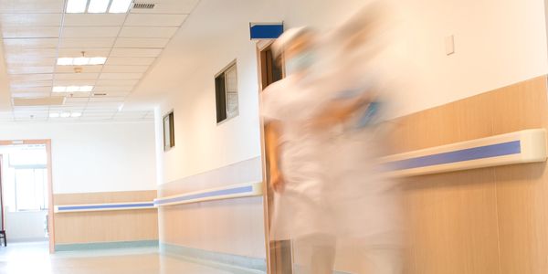 Blurred nurses walking in a hospital corridor.