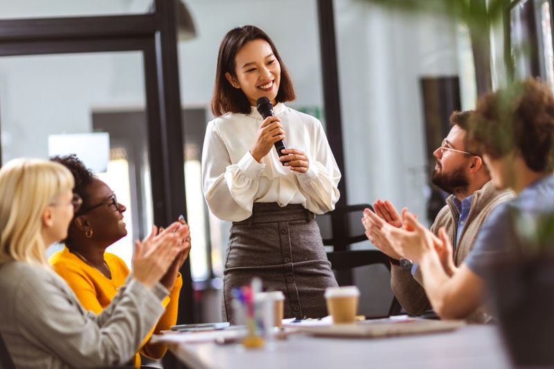 Asian business woman talking on the microphone to her colleagues.
