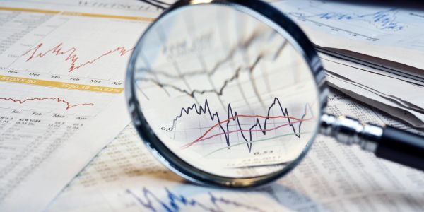 Magnifying glass over financial charts and graphs.