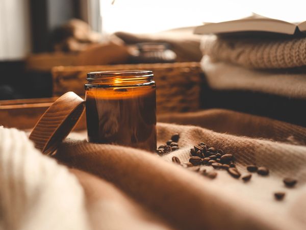 A cozy scene with a lit candle and coffee beans on a soft blanket.