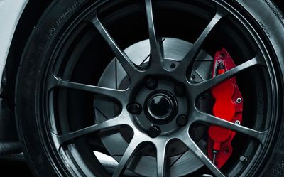 Close-up of a car wheel with a red brake caliper and sporty rim.