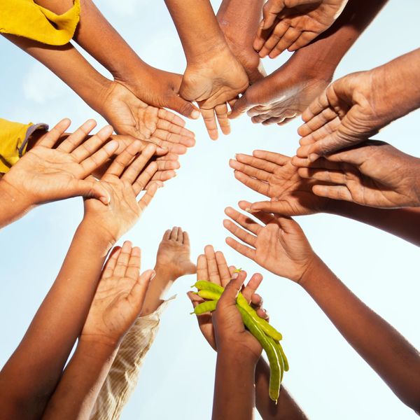 Hands joined together in a circle against the sky.