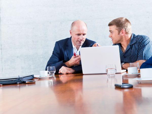 Two men collaborating over a laptop in a modern meeting room.