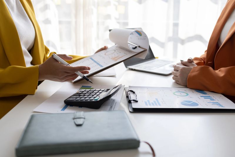 business women working on desk office with using a calculator to calculate the numbers tax, finance accountingresearch or financial strategy in company concept