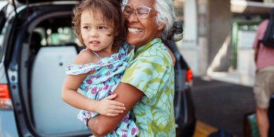Smiling elderly woman holding a young child.