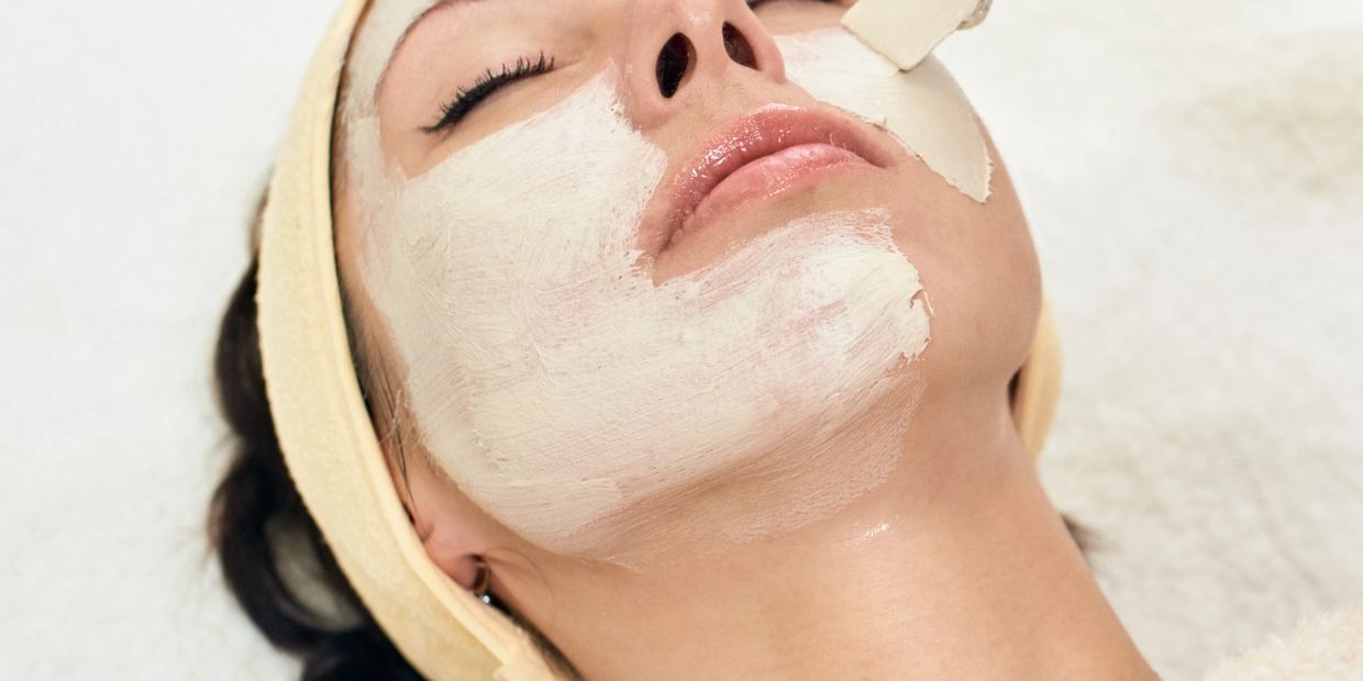 Woman relaxing with a white facial mask being applied.